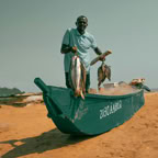 Ein Fischer präsentiert stolz seinen Fang an einem Sandstrand in Cabinda, Angola.